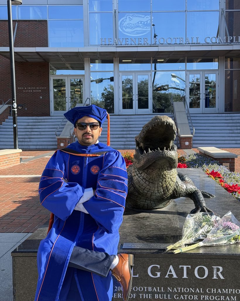 Dr. Utsab Ghimire in doctoral regalia by the University of Florida Gator statue